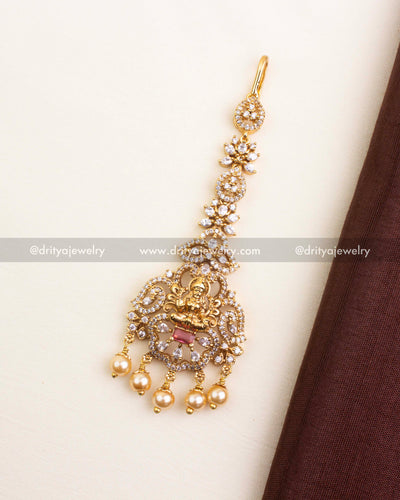 Temple-inspired maang tikka with red centerpiece, CZ accents, and pearl drops.