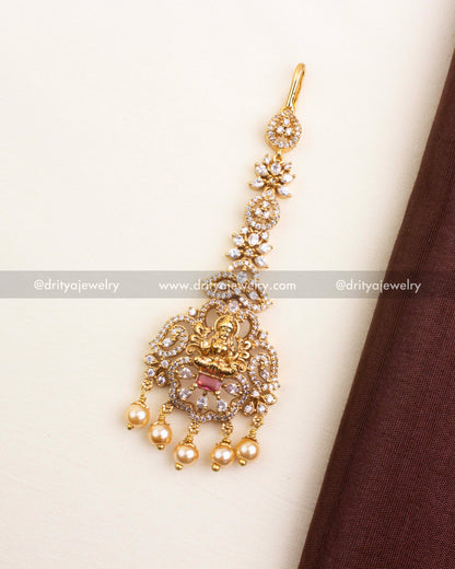 Temple-inspired maang tikka with red centerpiece, CZ accents, and pearl drops.