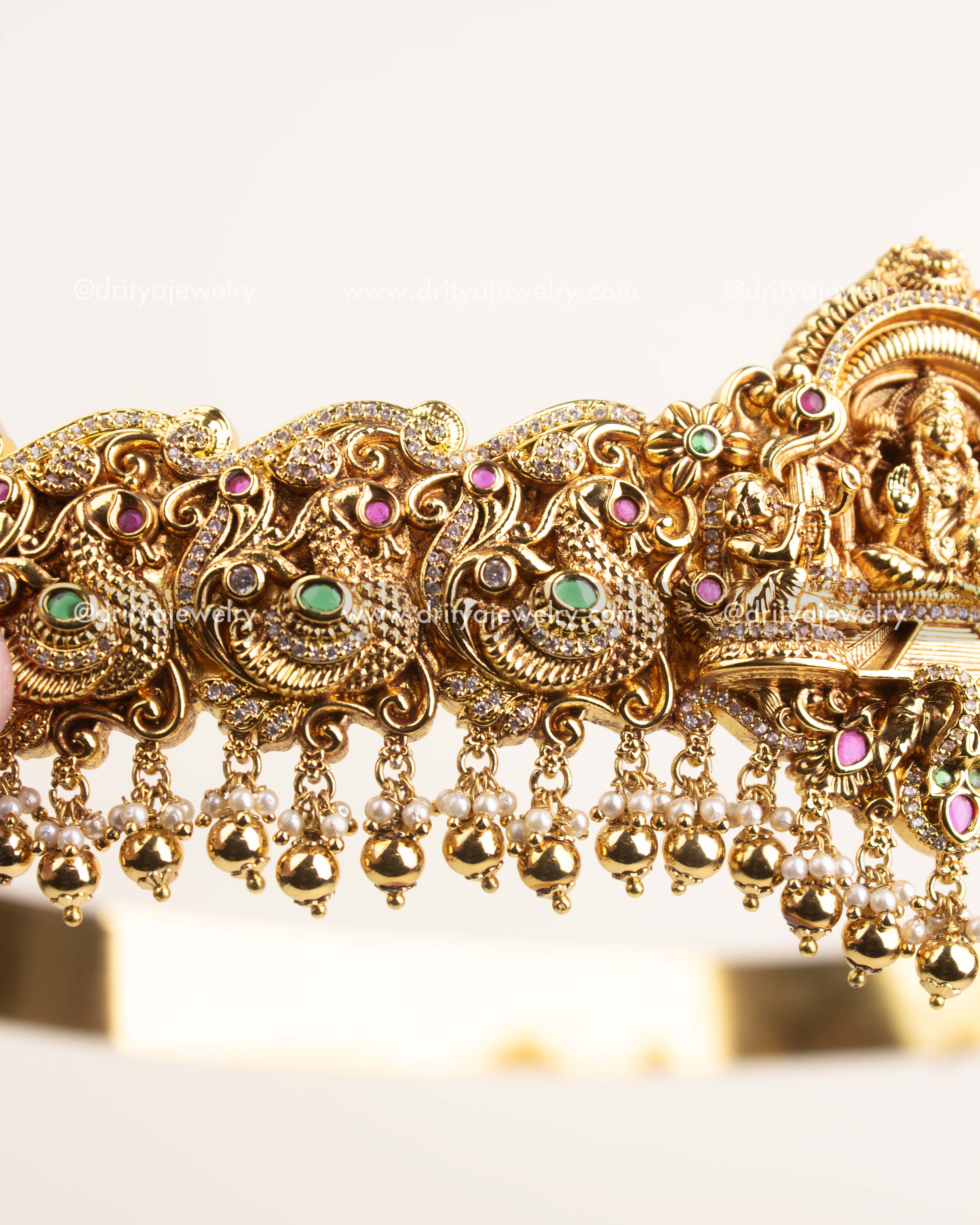 Side view showing ornate Nakshi craftsmanship, floral detailing, and hanging pearl beads.
