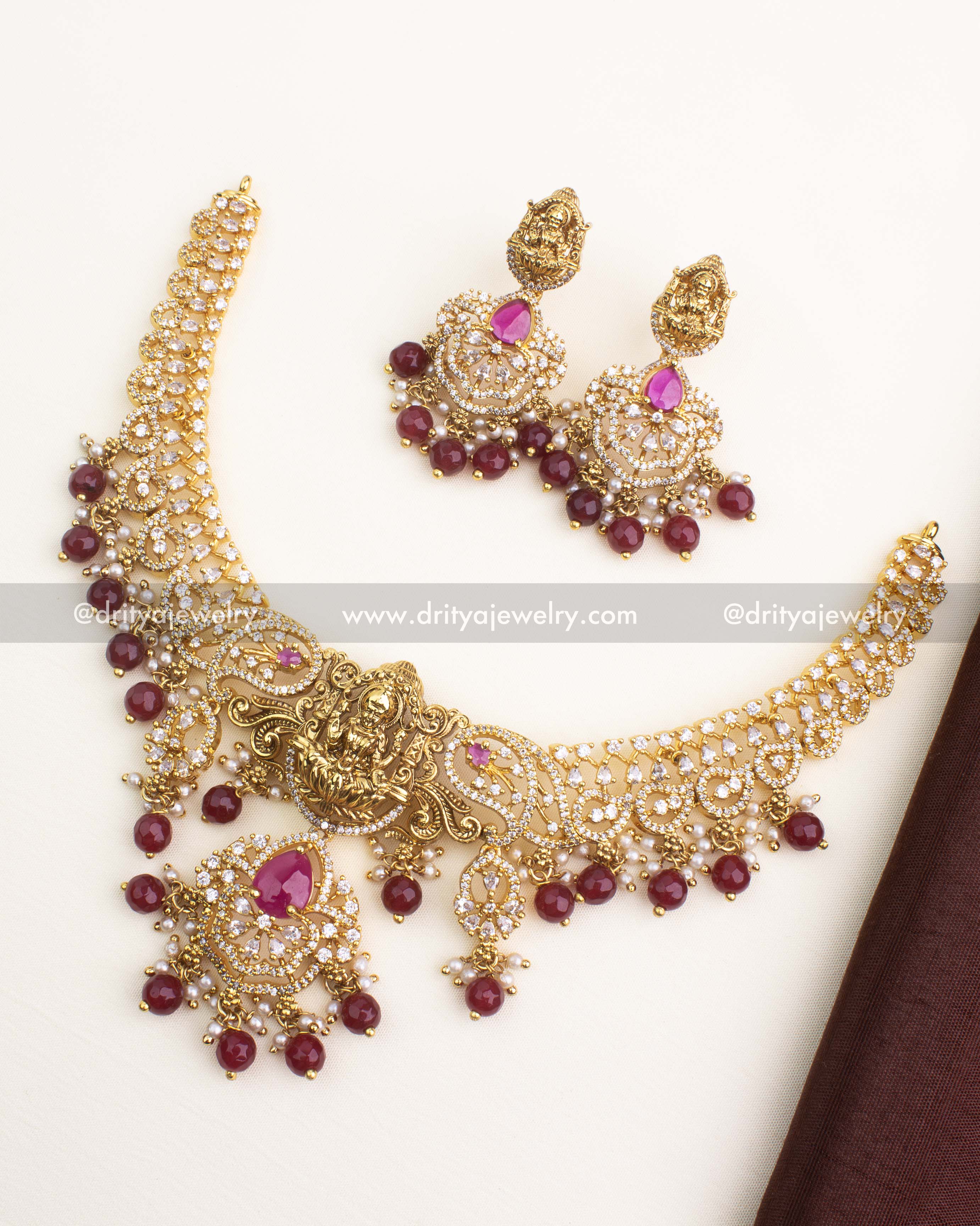 Gold temple short necklace set with nakshi Lakshmi pendant, CZ stones, and ruby red bead drops.