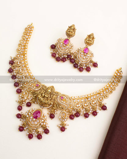 Gold temple short necklace set with nakshi Lakshmi pendant, CZ stones, and ruby red bead drops.
