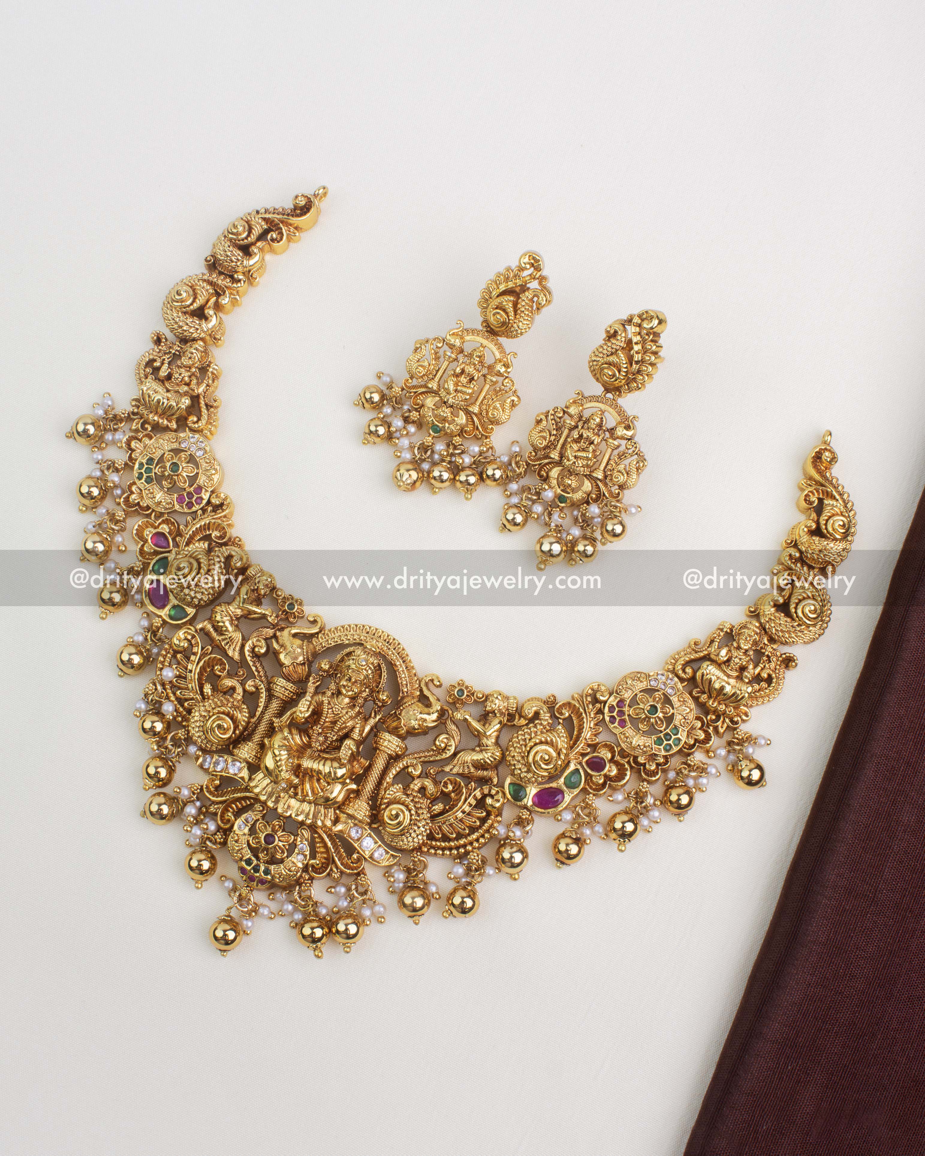 Gold-plated temple short necklace with Lakshmi pendant, ruby and emerald stones, and Nakshi detailing.