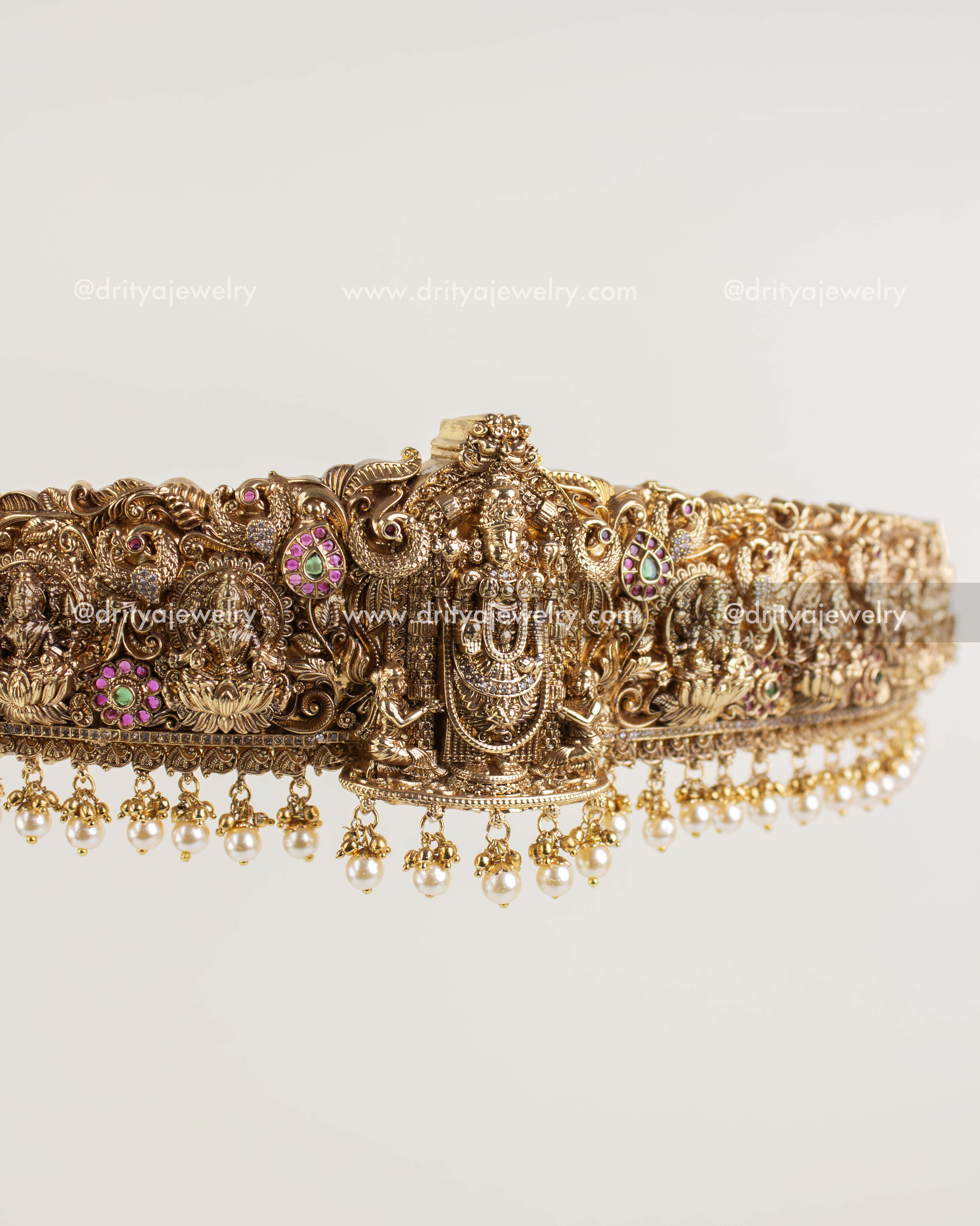 Temple-style gold waist belt featuring Lord Venkateshwara carving and pearl drop fringe.