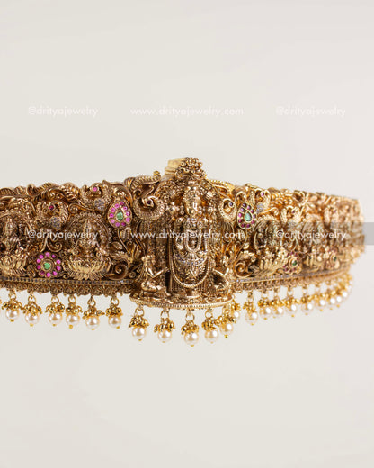 Temple-style gold waist belt featuring Lord Venkateshwara carving and pearl drop fringe.