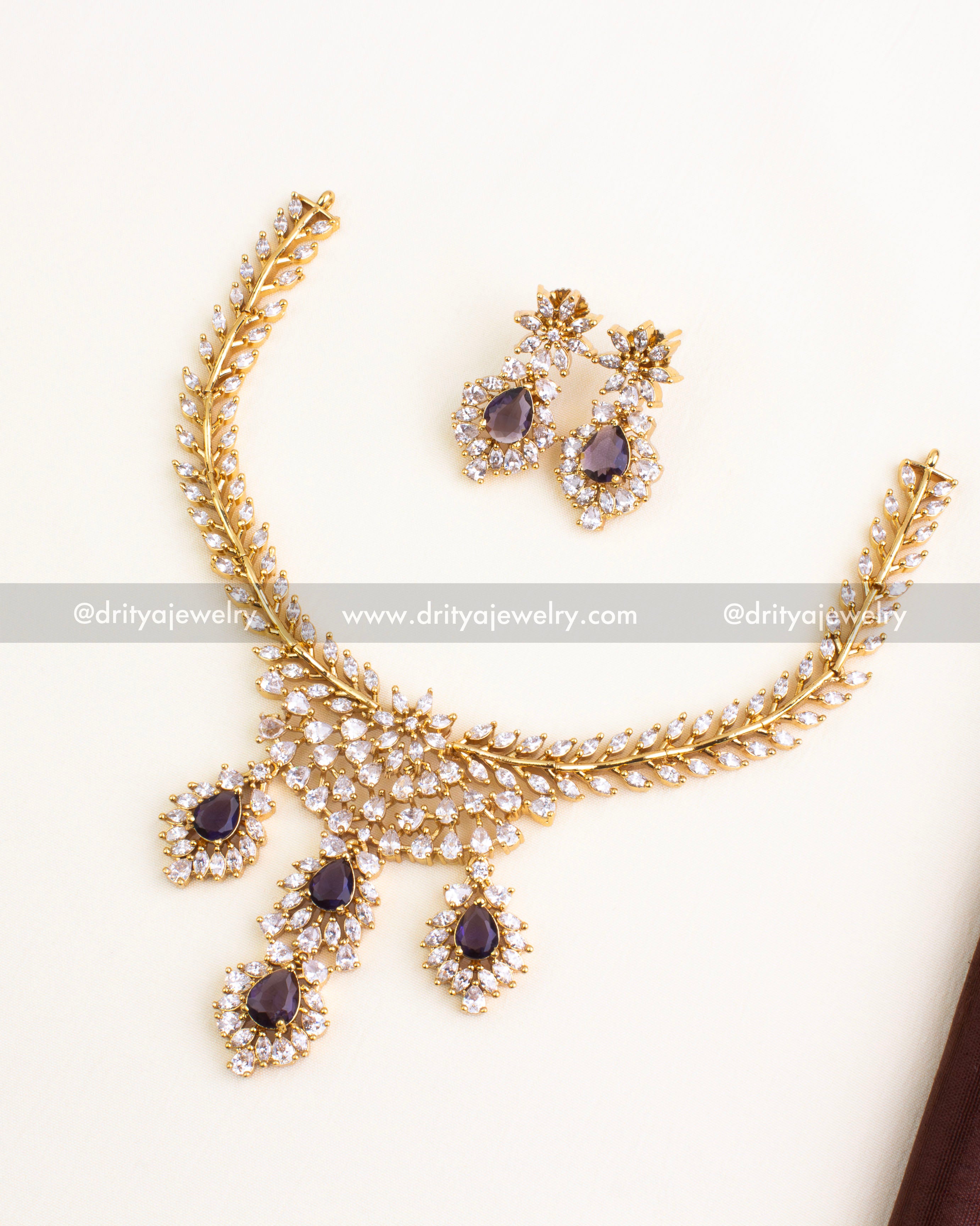 Floral gold necklace set with deep purple stones and diamond-like CZ work.