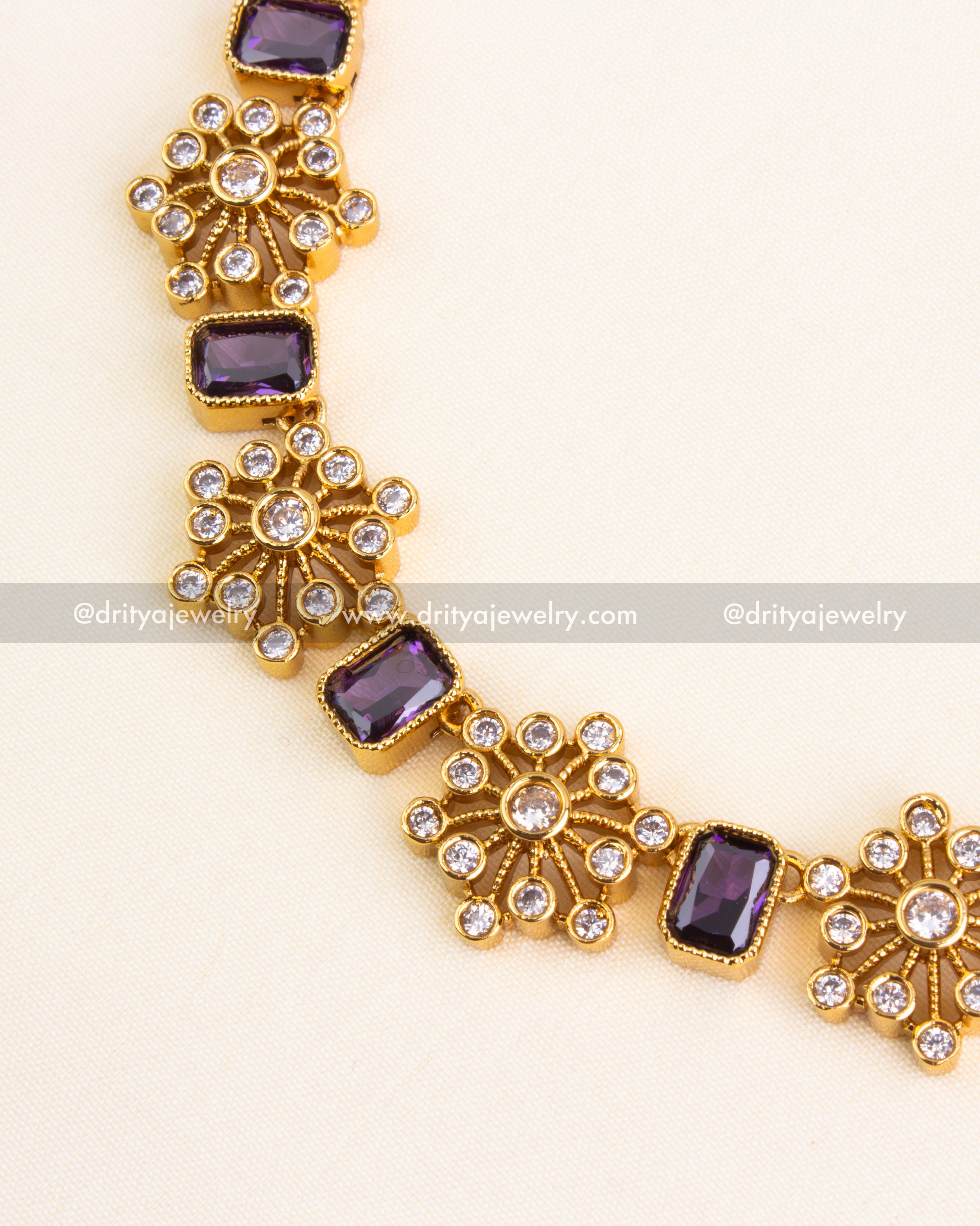 Close-up of short necklace with alternating purple stones and AD floral designs