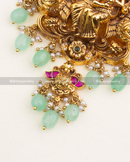 Close-up of Radha Krishna temple pendant showcasing nakshi detailing, CZ stones, kemp enamel work, and mint-green bead drops.