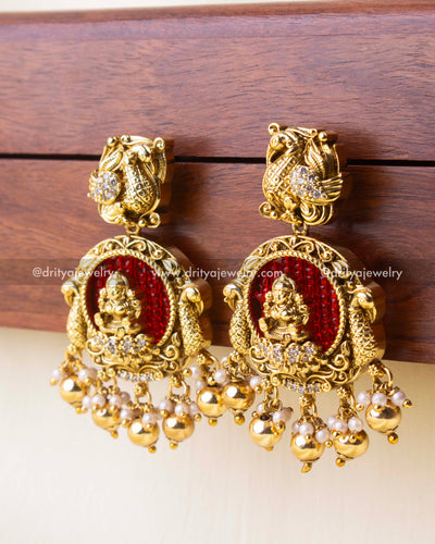 Antique gold earrings featuring Lakshmi and red bead detailing.