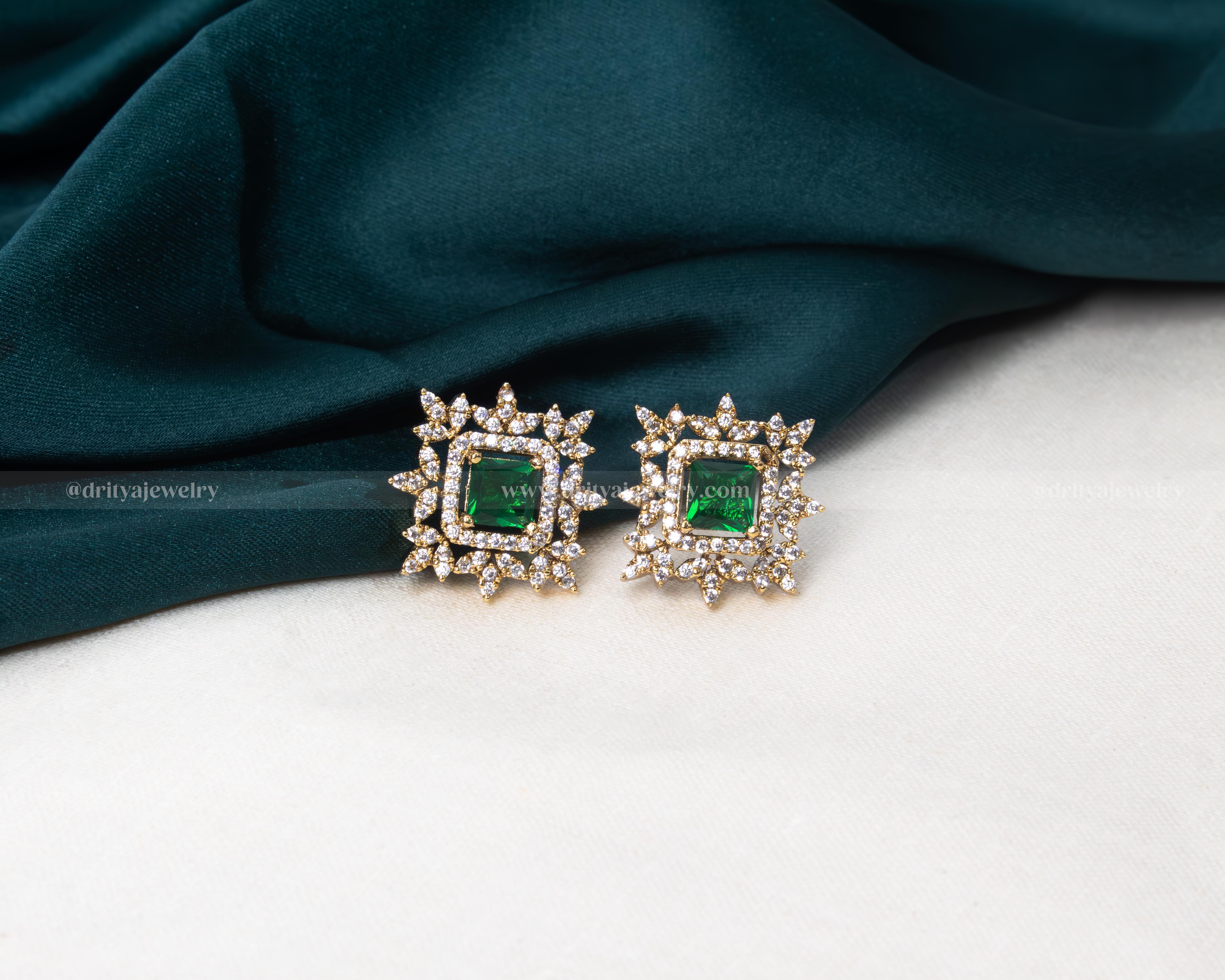 Elegant gold-tone stud earrings with a faux emerald center and sparkling cubic zirconia halo, perfect for adding a touch of luxury to any attire.