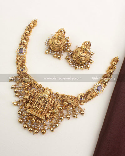 Temple-style short necklace with Lakshmi motif, antique gold finish, and matching jhumkas from Dritya Jewelry.