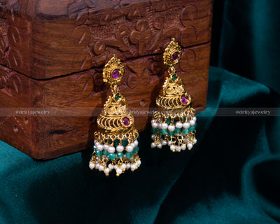 Elegant gold-plated Jhumka earrings with synthetic ruby and emerald gemstones, accented with cascading pearls, perfect for weddings and formal events.