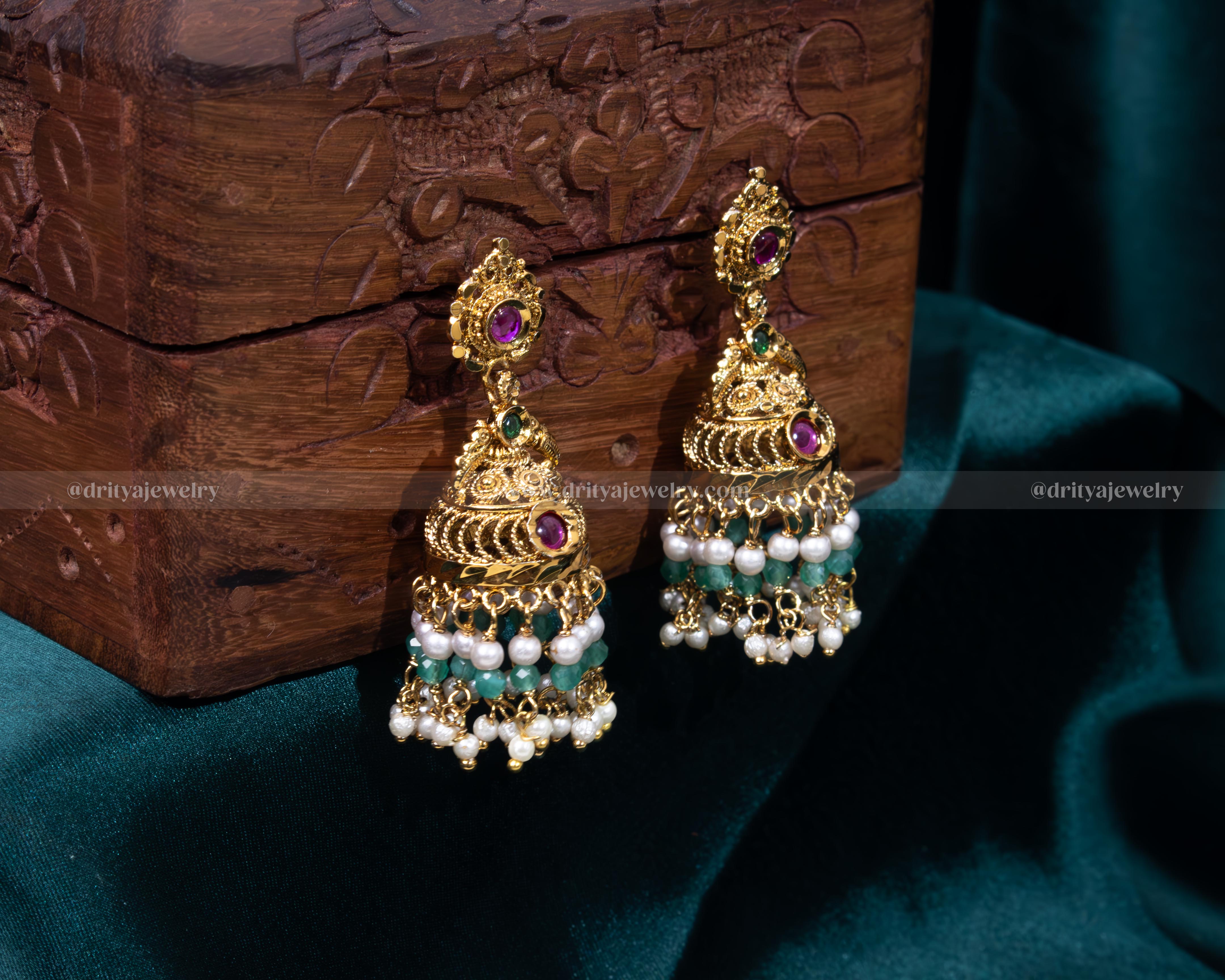 Elegant gold-plated Jhumka earrings with synthetic ruby and emerald gemstones, accented with cascading pearls, perfect for weddings and formal events.