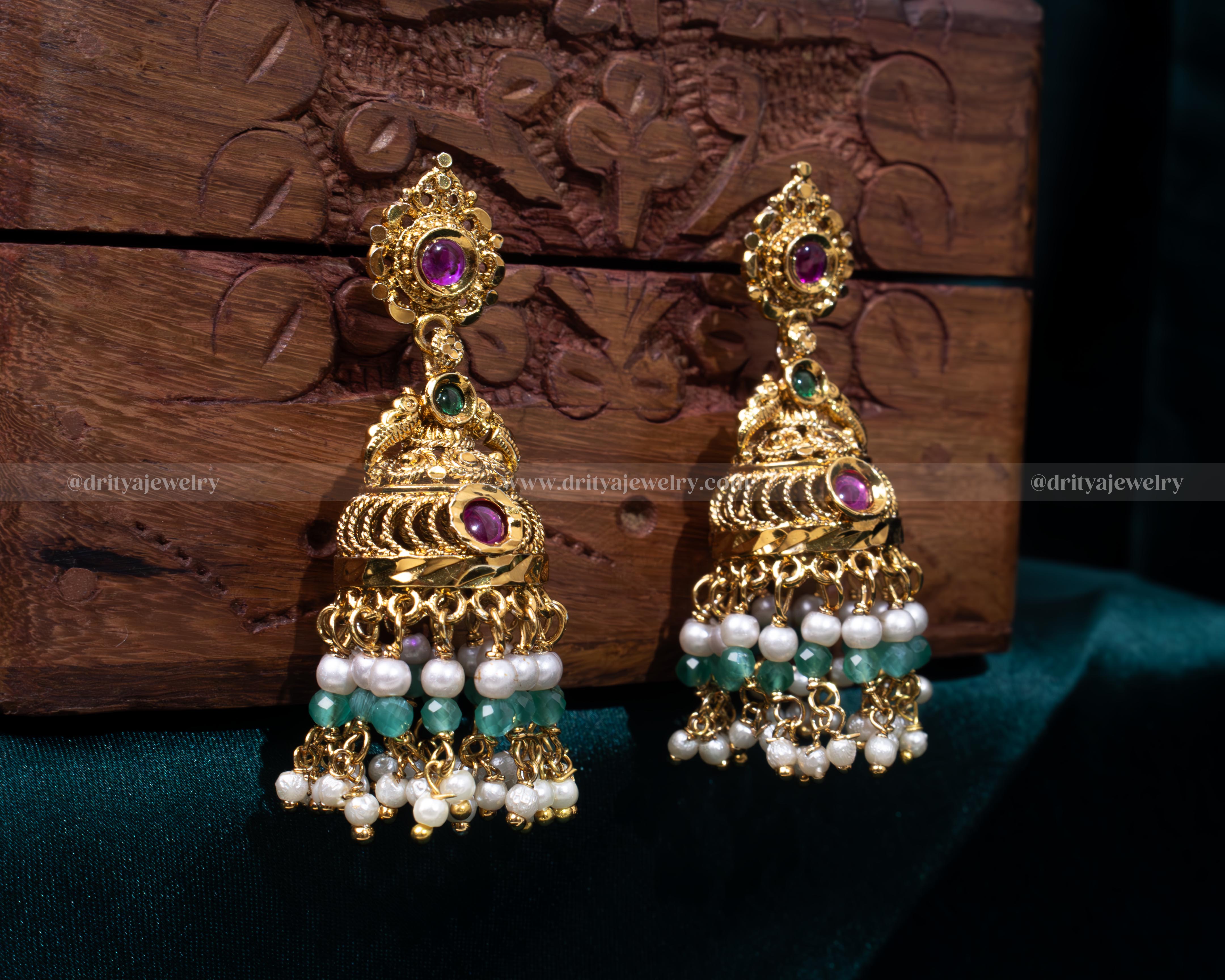 Elegant gold-plated Jhumka earrings with synthetic ruby and emerald gemstones, accented with cascading pearls, perfect for weddings and formal events.