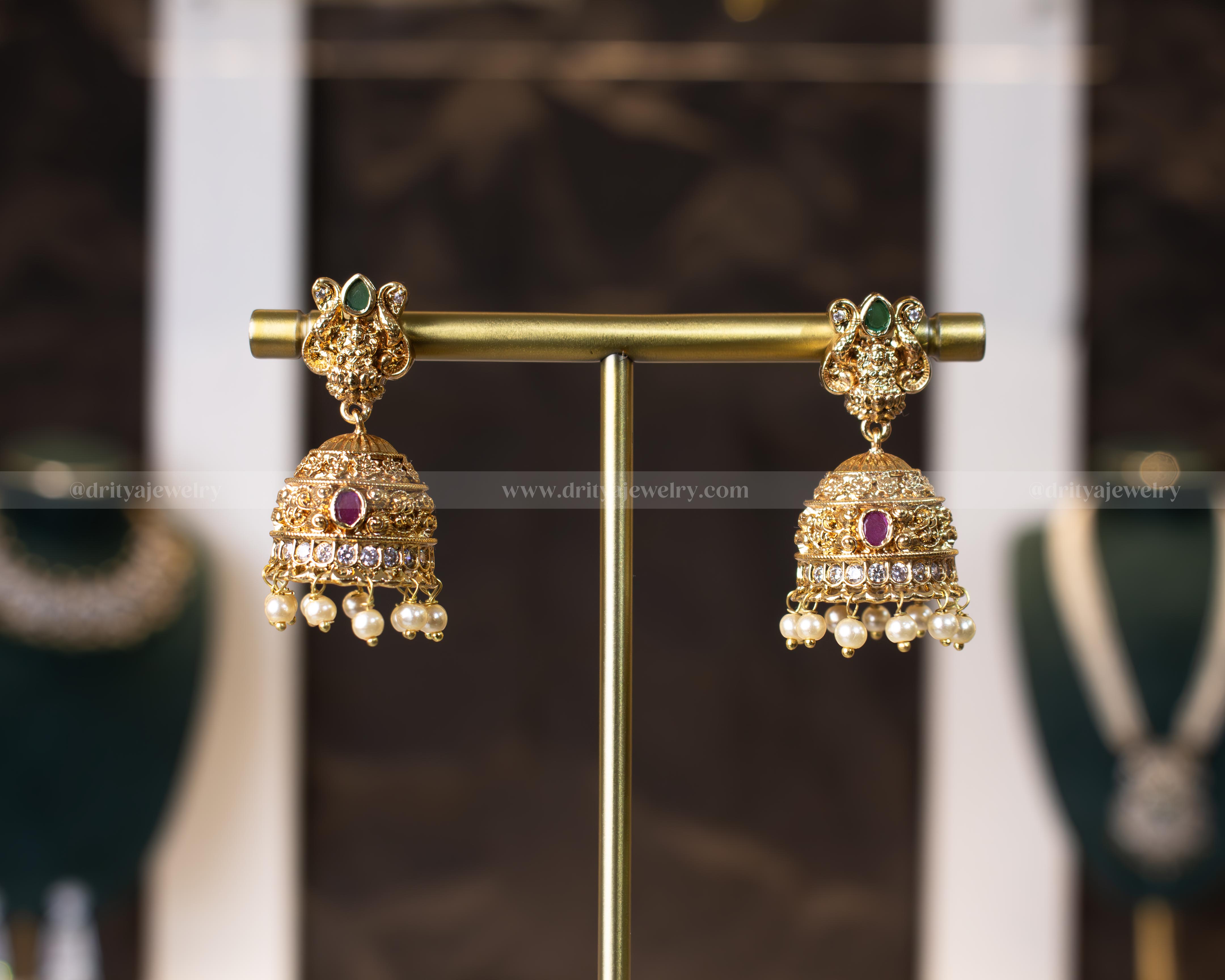 Dritya Jewelry's Royal Blossom Jhumka Earrings featuring floral motifs with faux emerald and ruby gemstones, intricate gold patterns, and imitation pearl droplets.