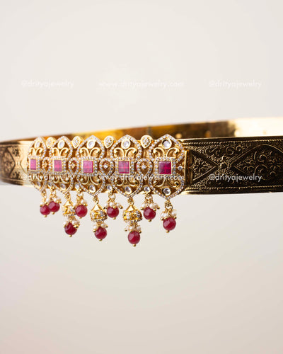 Close-up of CZ-studded vaddanam with cushion-cut ruby stones and engraved gold band