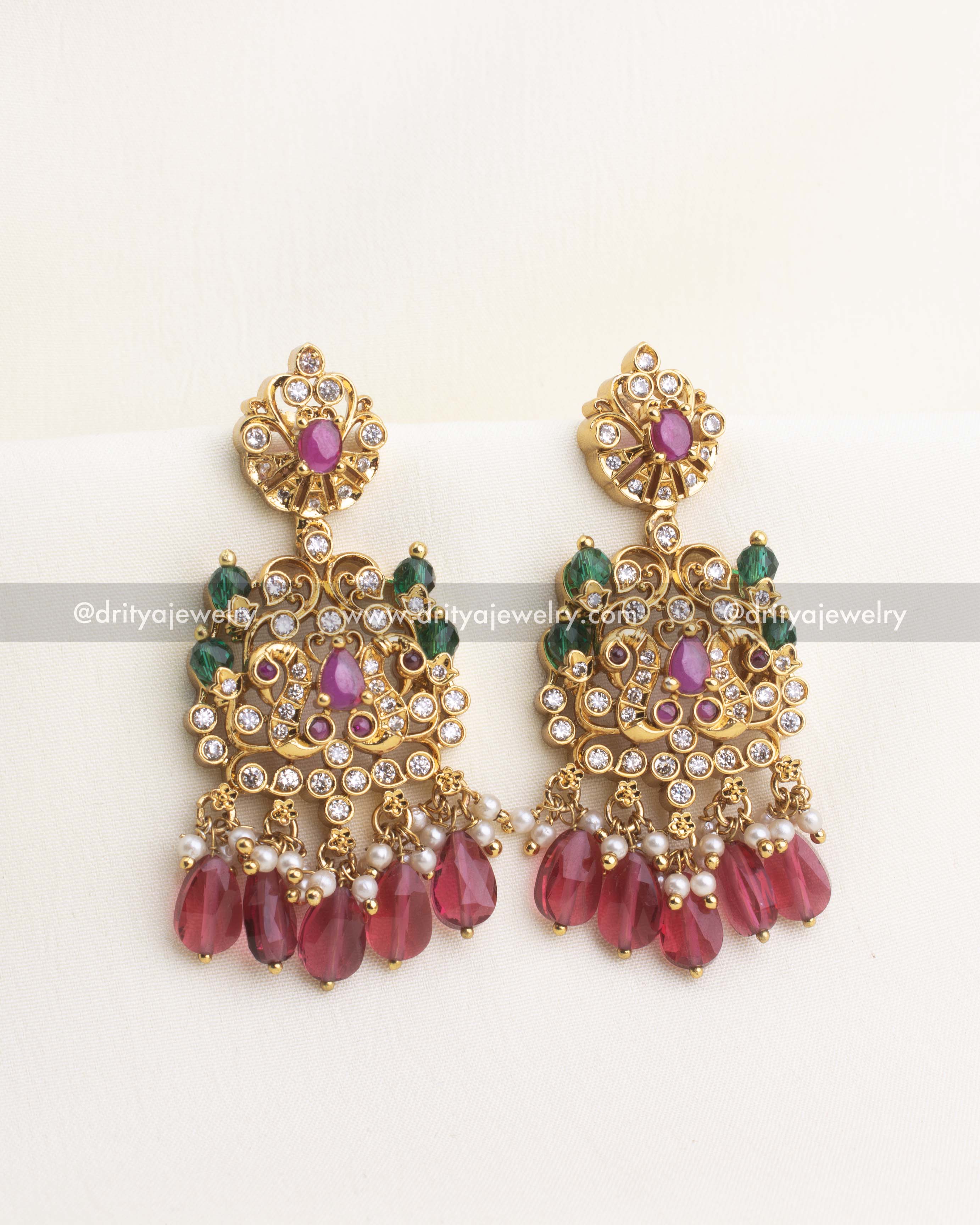 Ruby teardrop bead chandbali earrings with gold-plated AD studded motifs.