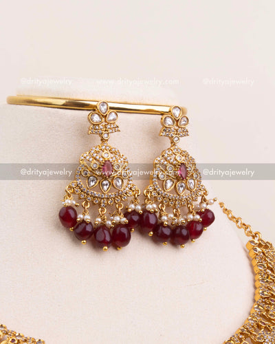 Pair of kundan earrings featuring ruby red accents and maroon bead tassels.