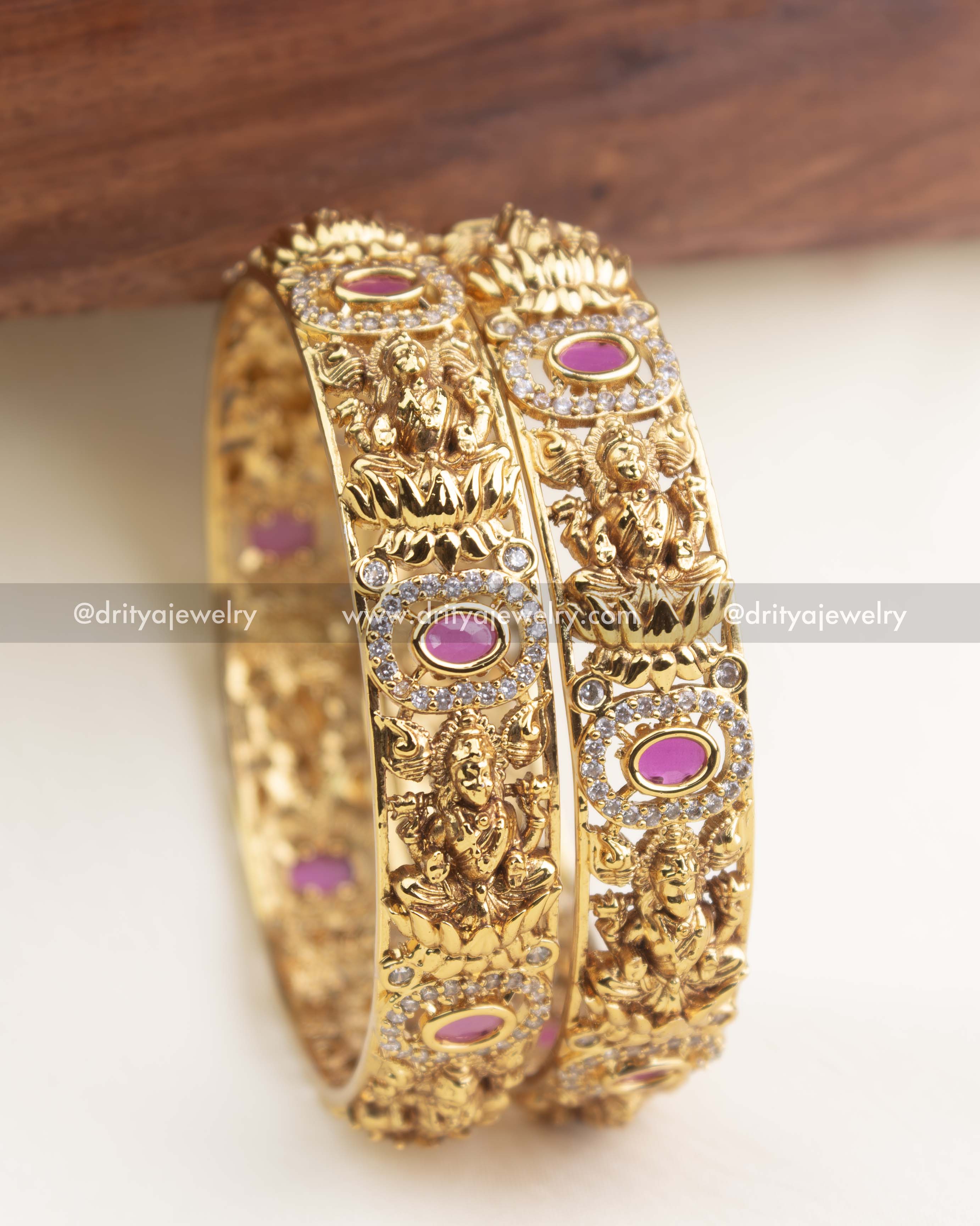 Side profile of temple-style bangles with antique gold motifs and oval ruby pink gemstones