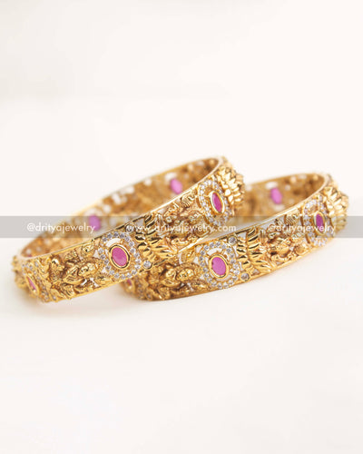 Gold temple bangles featuring ruby pink stones, goddess carvings, and AD stone embellishments