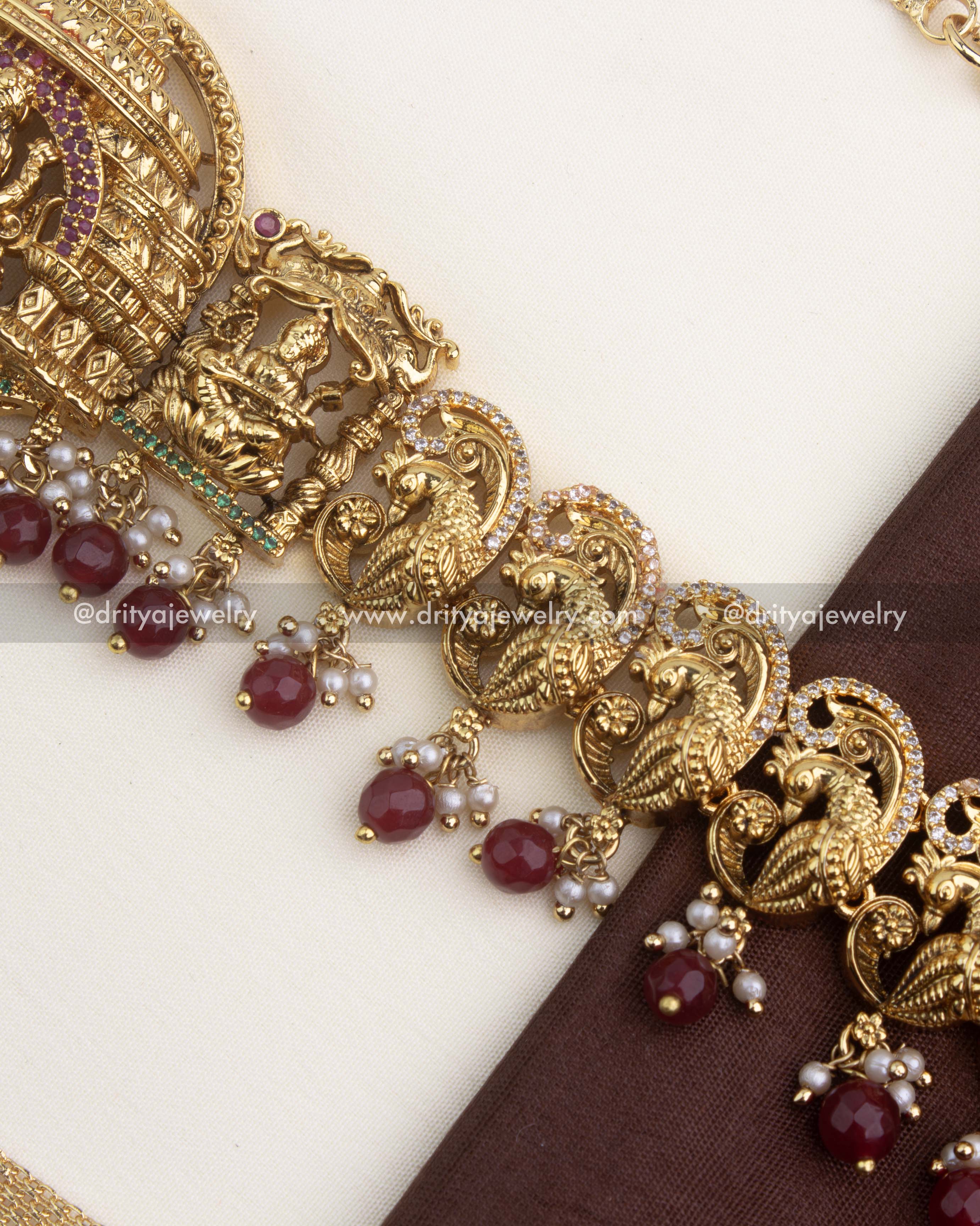 Detailed view of ruby red bead drops with pearls under the antique peacock nakshi design.
