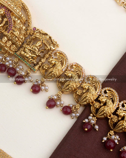 Detailed view of ruby red bead drops with pearls under the antique peacock nakshi design.