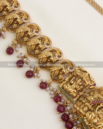 Detailed view of ruby red bead drops with pearls under the antique peacock nakshi design.