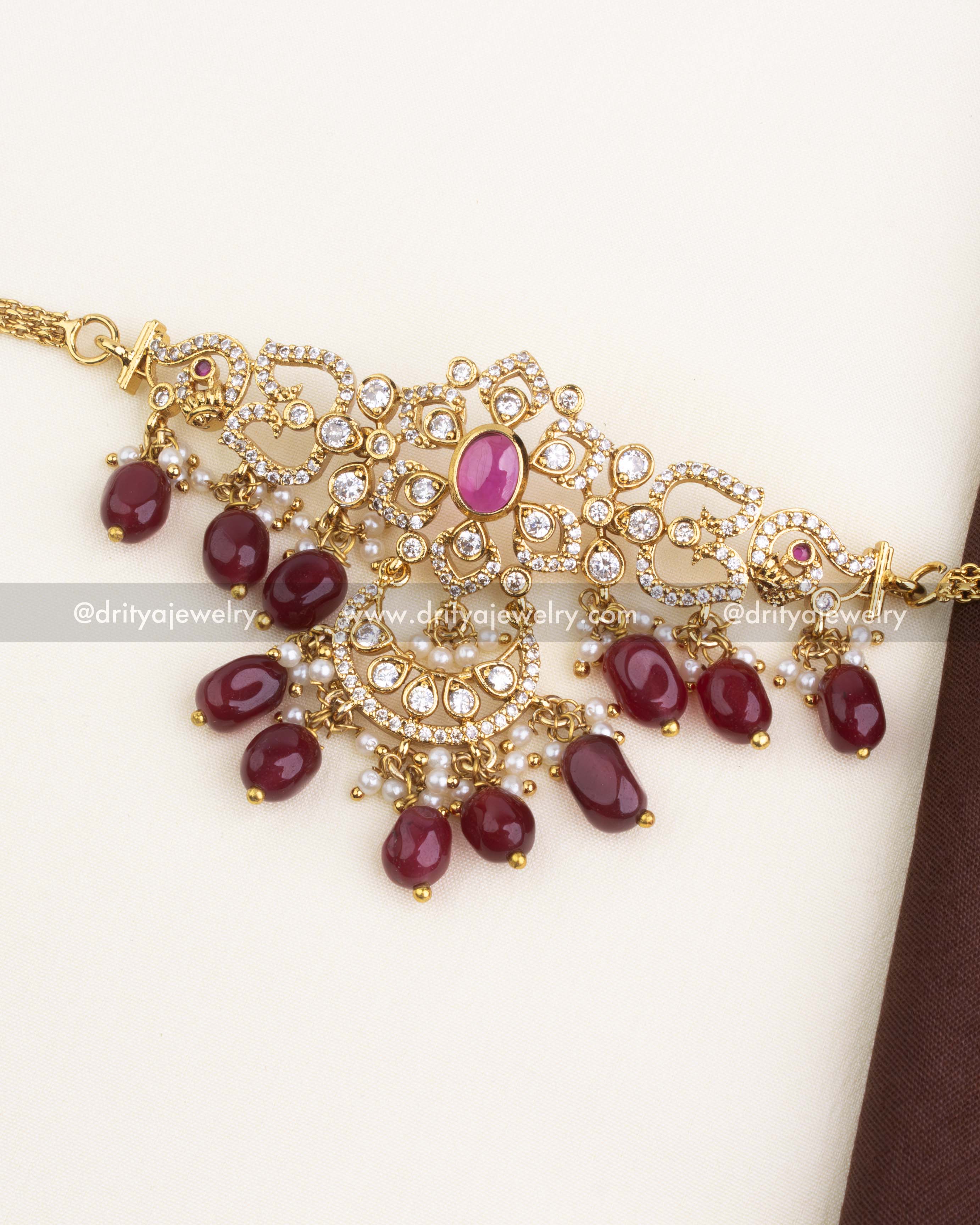 Ornate gold-plated choker with ruby red beads and CZ stones, paired with jhumkas.