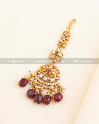 Bridal maang tikka in ruby red kundan design with pearl and maroon bead embellishments.