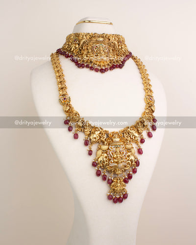 Bridal jewelry set in ruby red with antique Lakshmi pendant, peacock carvings, and temple design.