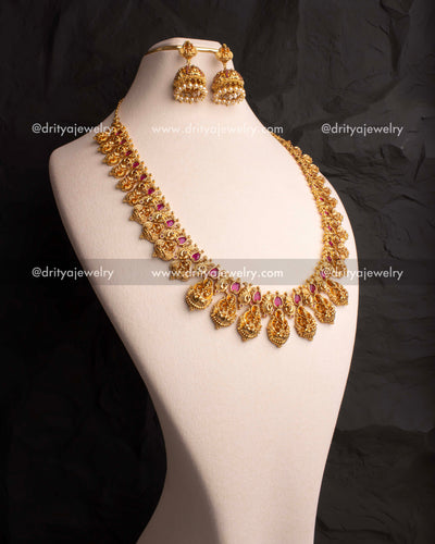 Traditional long haram set adorned with ruby red CZ stones and matching jhumkas.