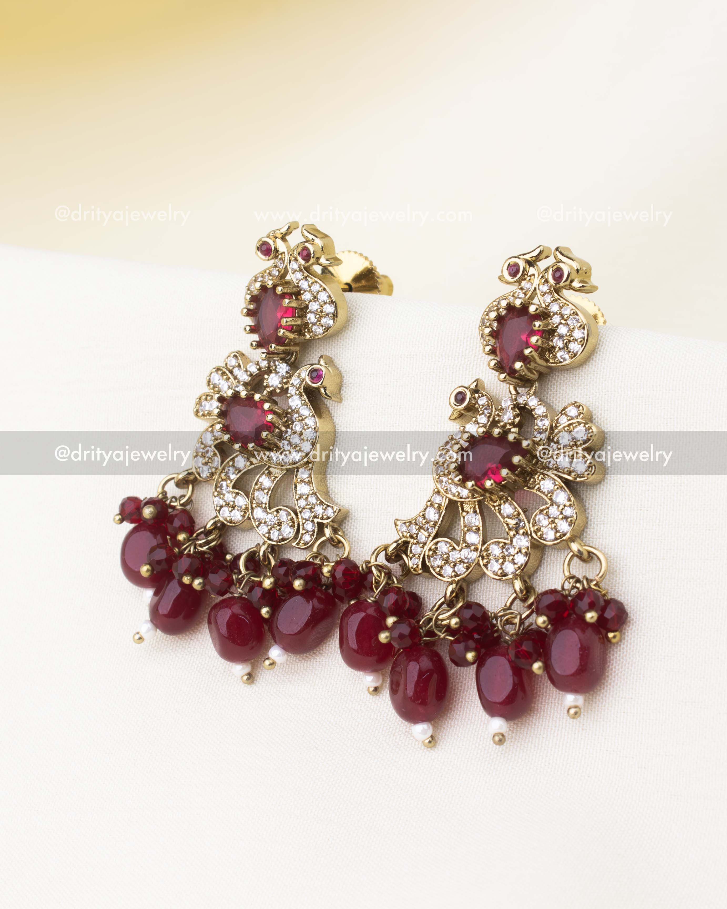 Victorian-inspired earrings with ruby red stones, CZ detailing, and bead hangings.