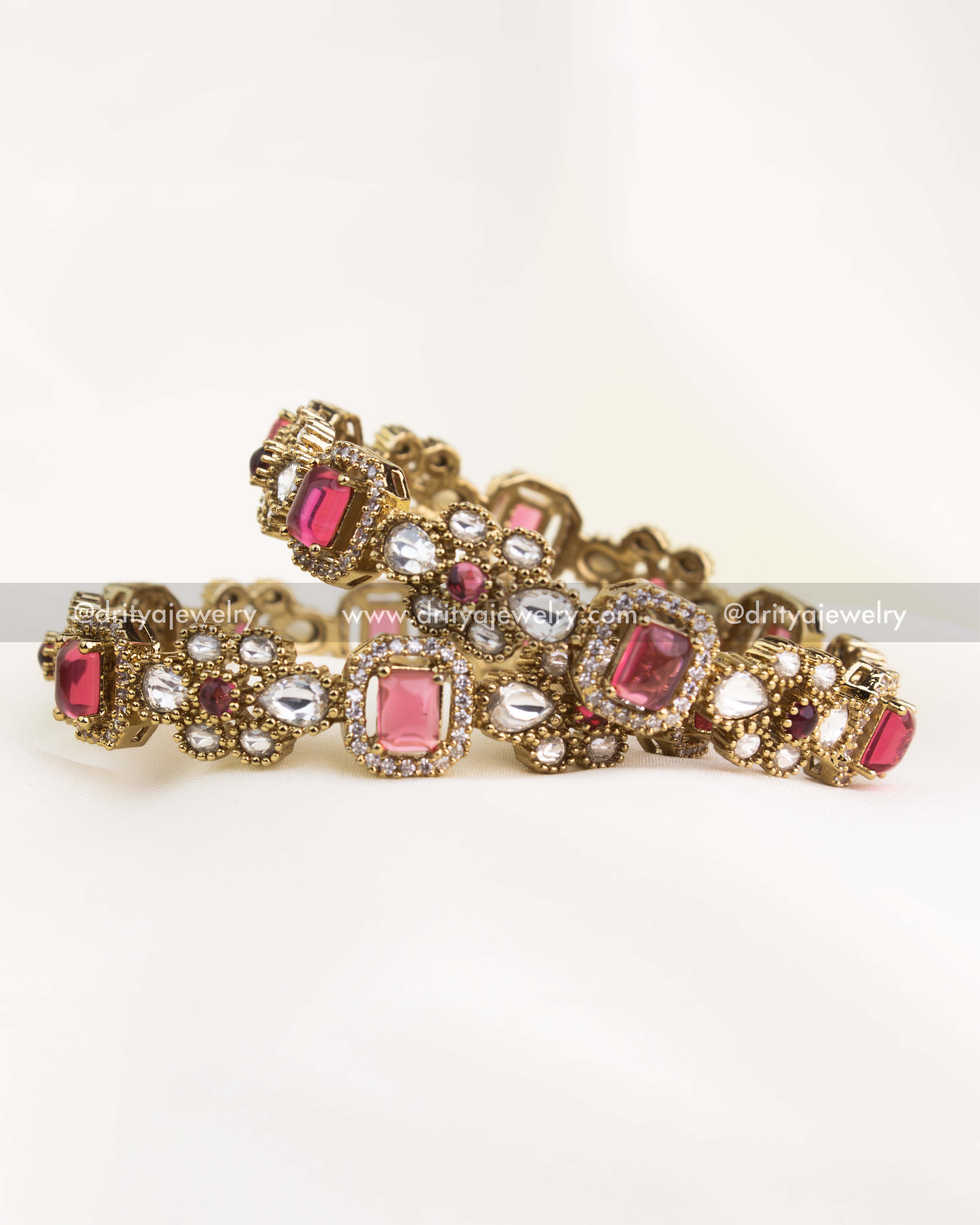 Victorian-inspired gold-plated bangles adorned with ruby red and white kundan stones for a royal festive look.