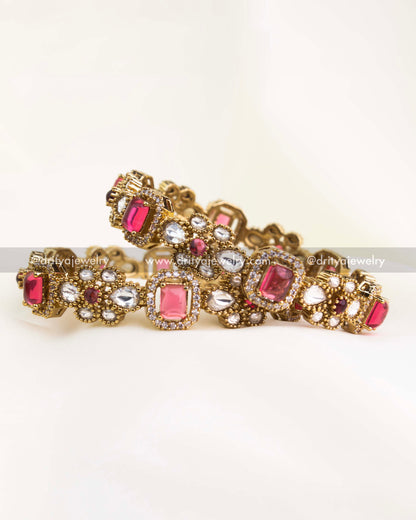 Victorian-inspired gold-plated bangles adorned with ruby red and white kundan stones for a royal festive look.
