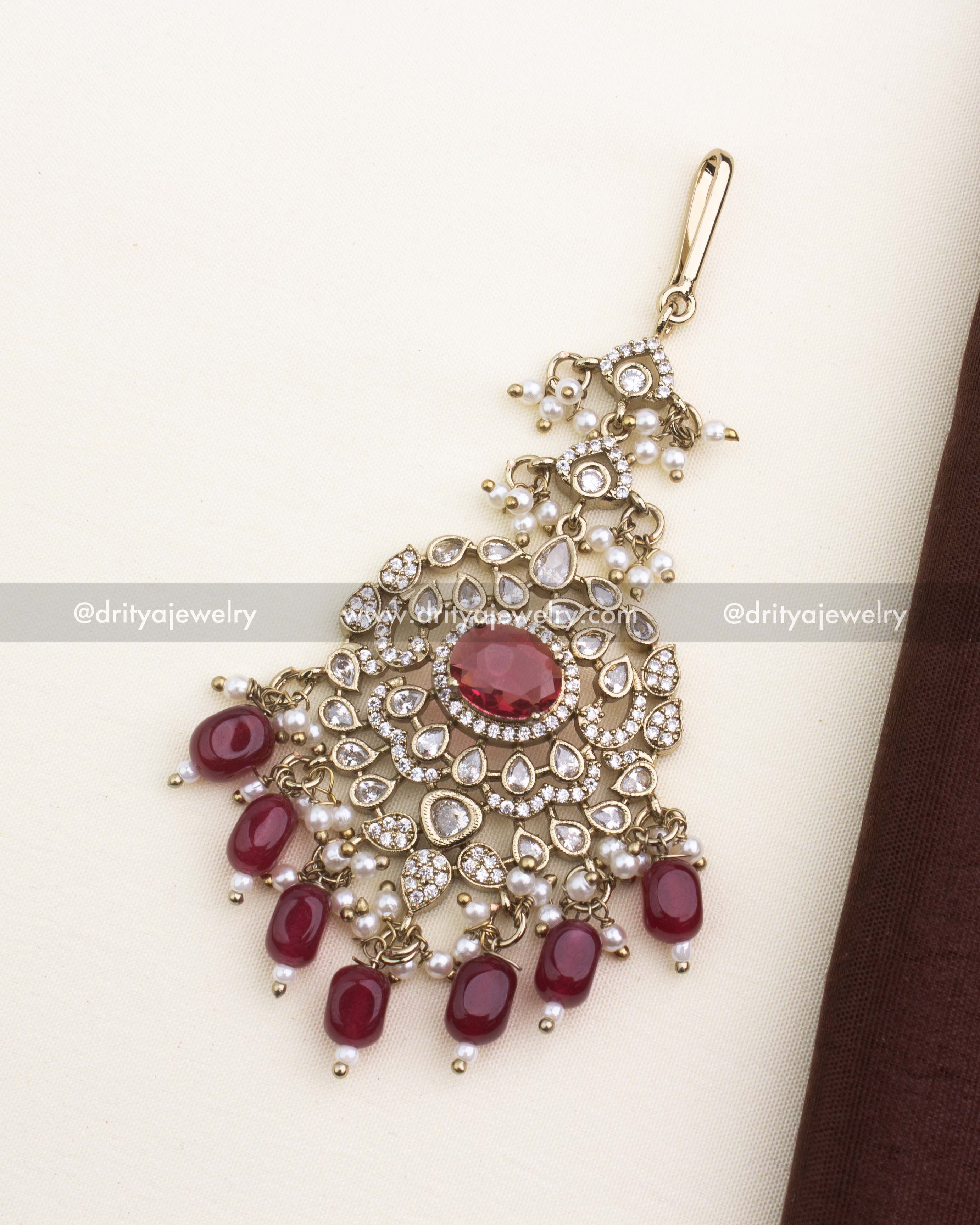 Ruby red maang tikka with antique Victorian detailing, AD stones, and pearl drops.