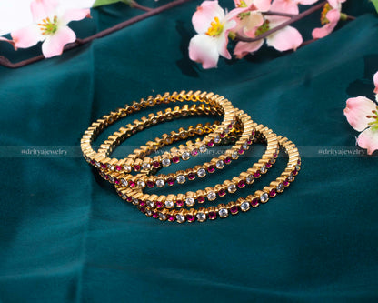 Ruby Bangle Set by Dritya Jewelry, featuring deep red rubies complemented by a luxurious gold setting.