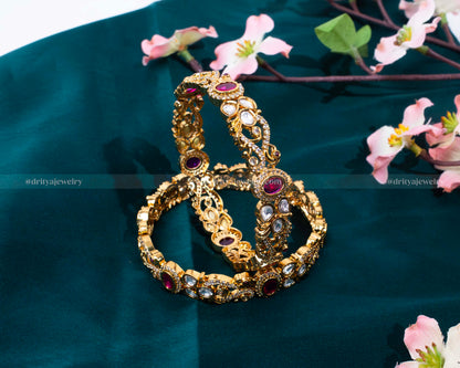 Luxurious bangle set adorned with rubies and diamonds in a golden frame by Dritya Jewelry.