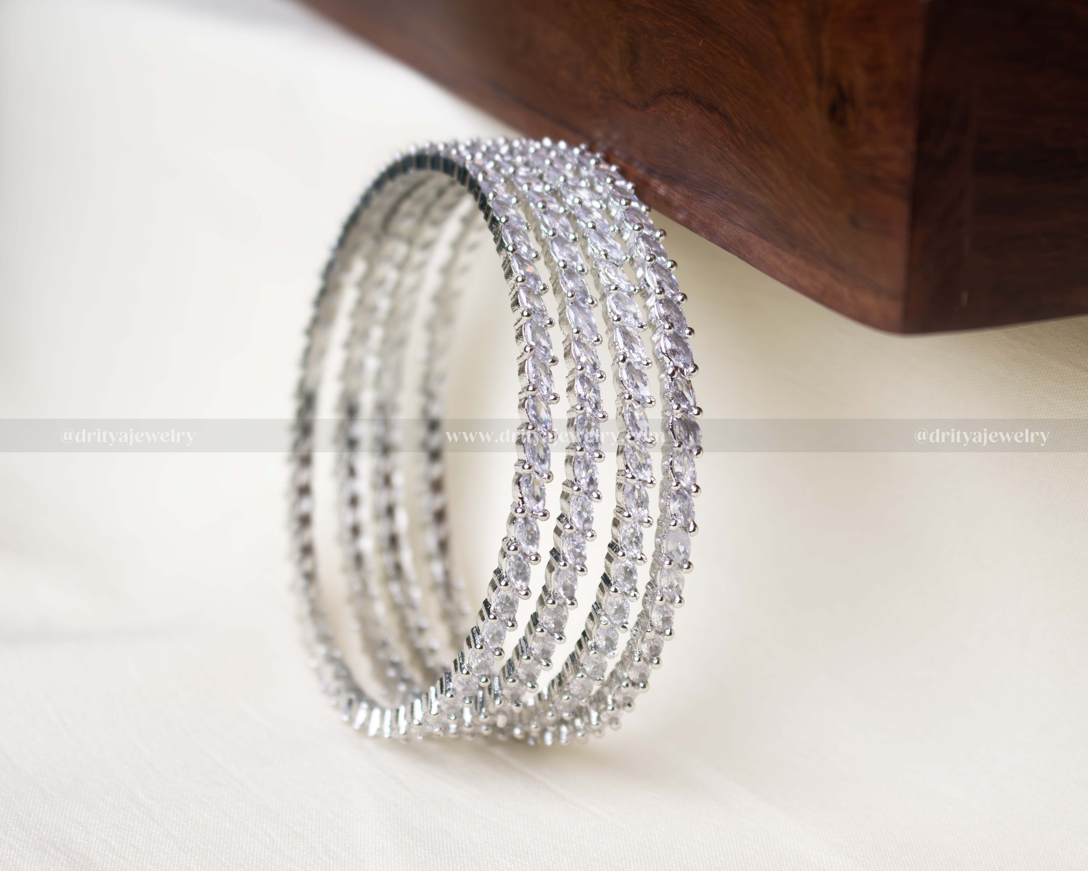 Set of 4 elegant zircon bangles with silver polish and sparkling stones, perfect for weddings and festive occasions.