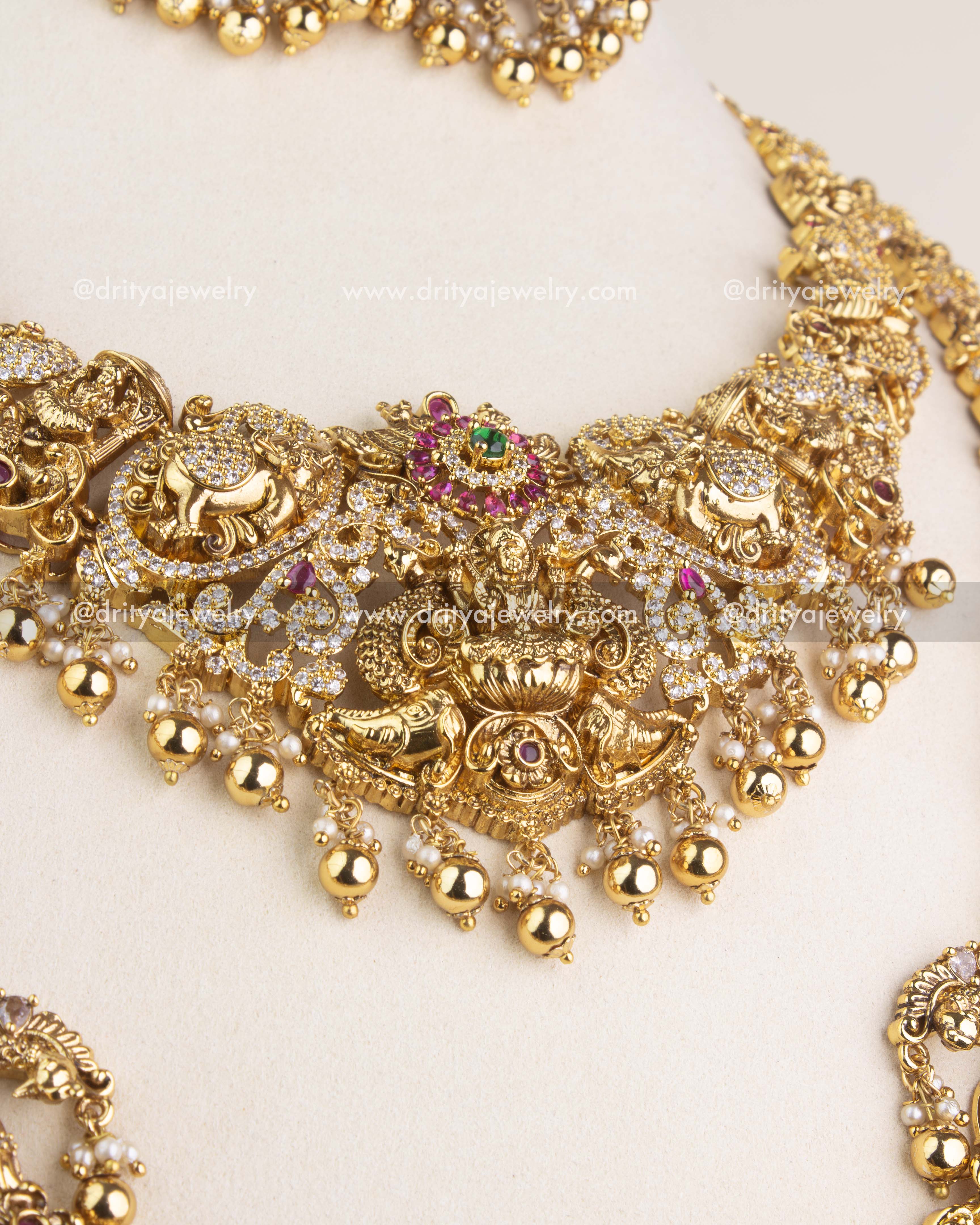 Close-up of short Nakshi necklace with goddess Lakshmi motif, ruby stones, and bead hangings.