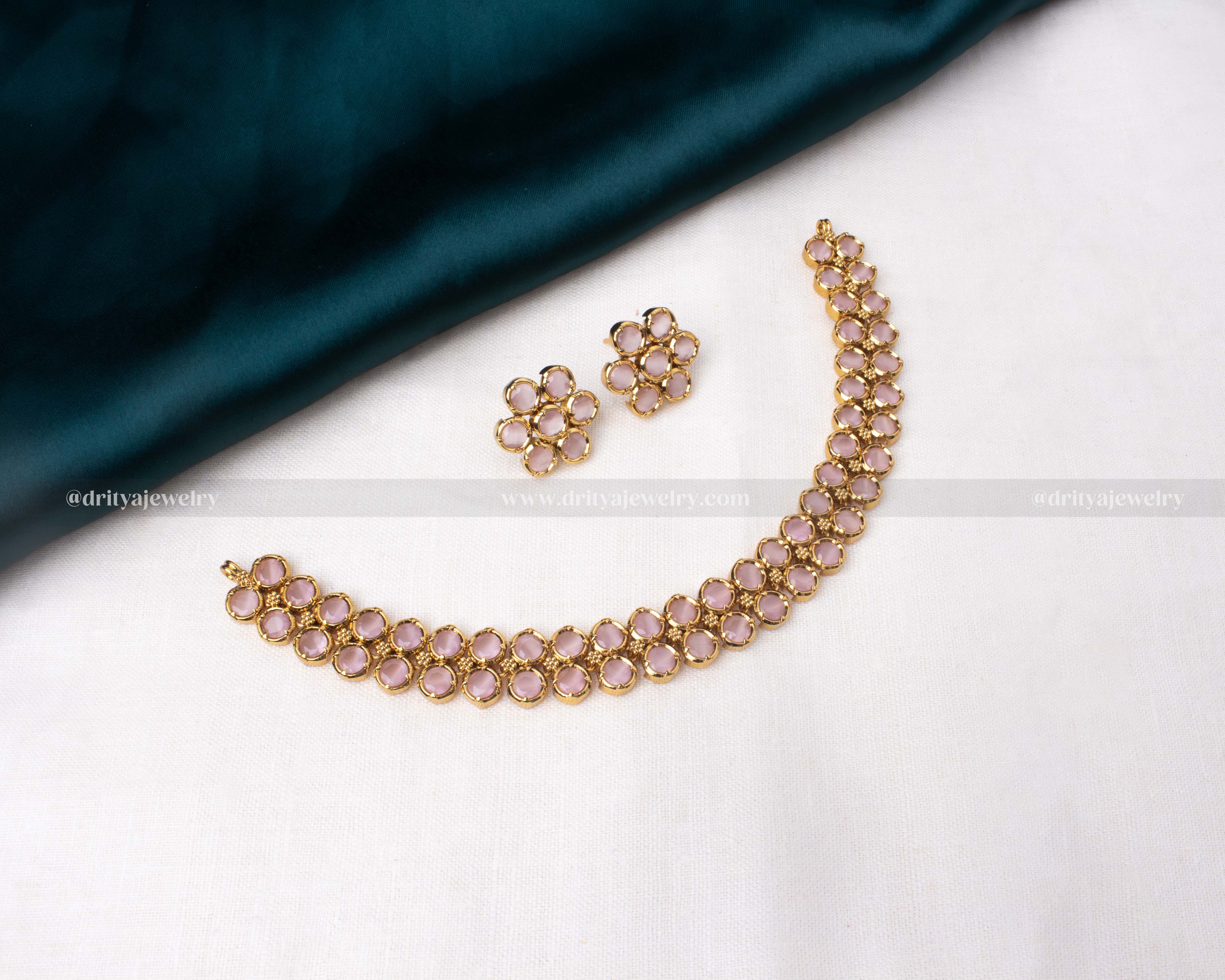 Short necklace set with blush pink stones and matching earrings in a gold-toned frame.