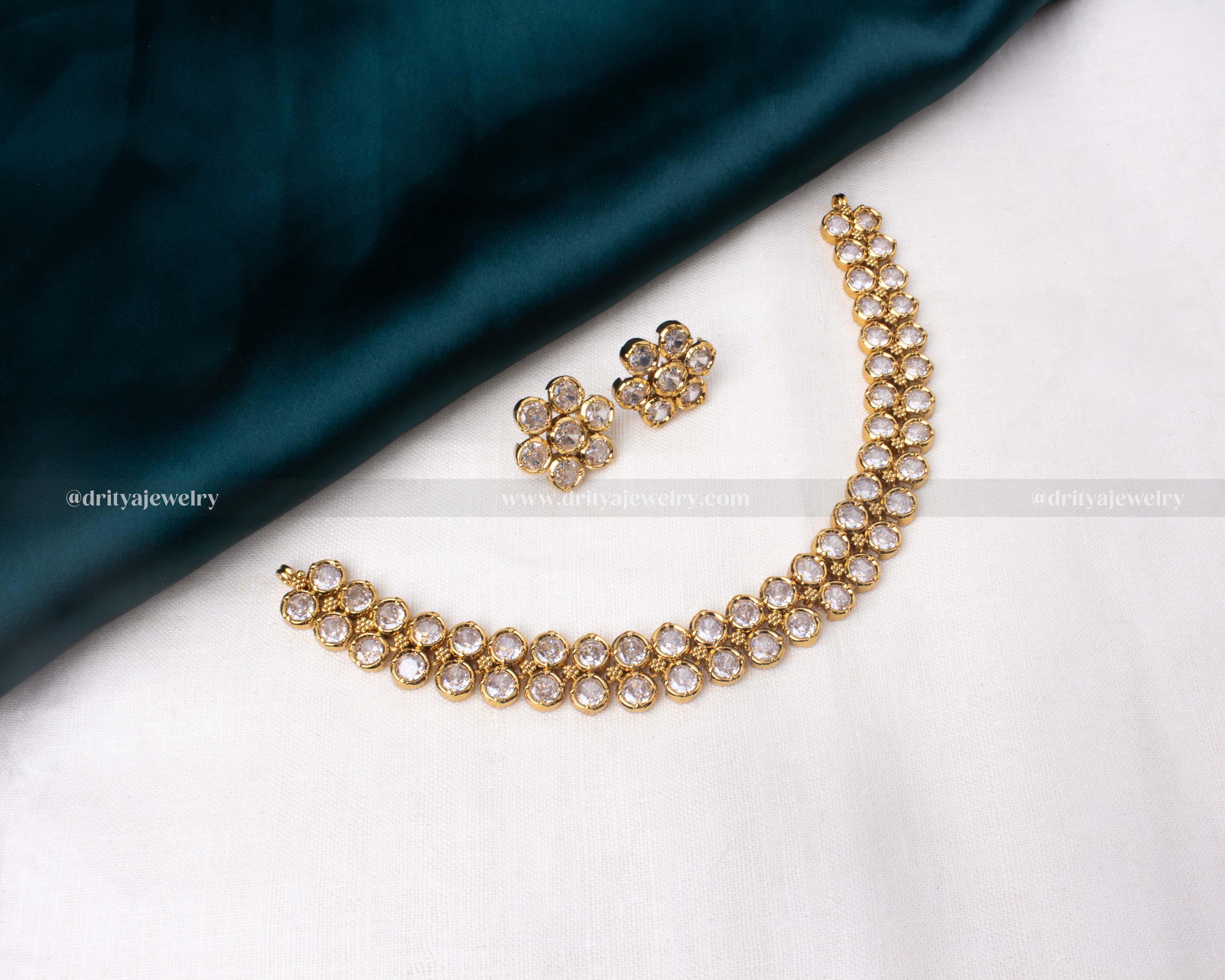 Short necklace set with white stones and matching earrings in a gold-toned frame.