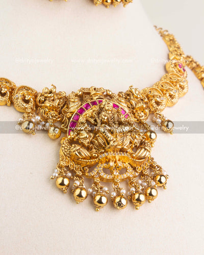 Detailed view of Lakshmi motif pendant with ruby kemp stones, peacock carvings, and pearl drops.