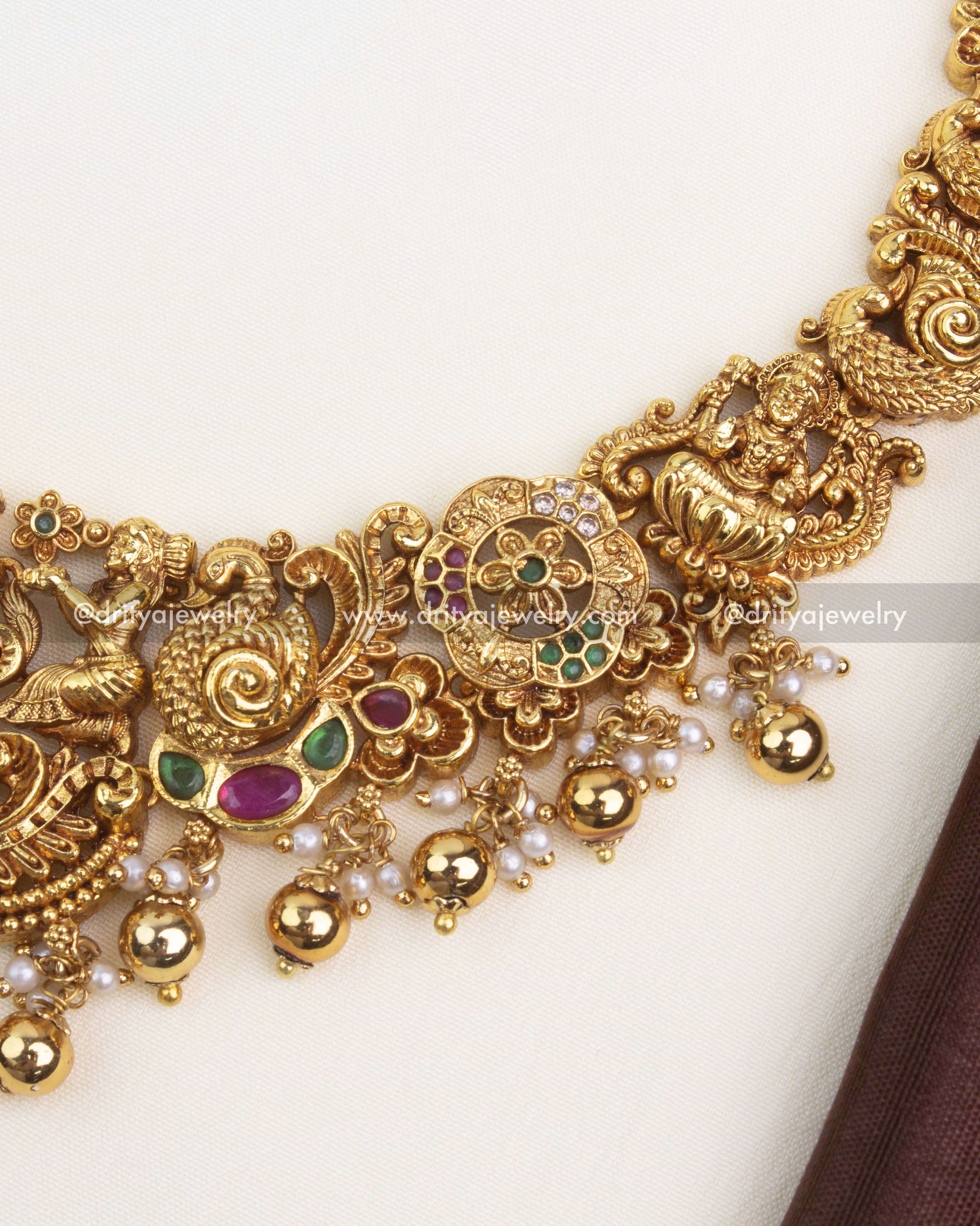 Intricate Nakshi Lakshmi pendant with peacocks, floral motifs, and antique gold polish.