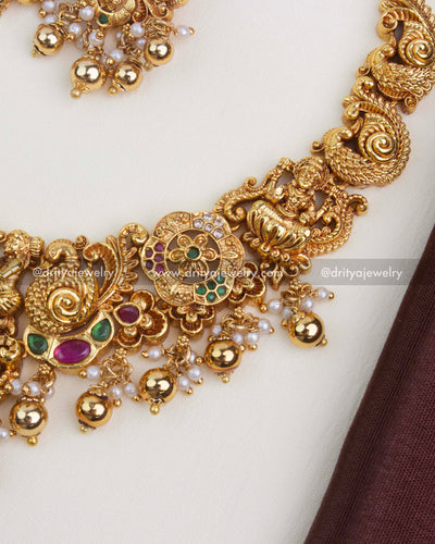Intricate Nakshi Lakshmi pendant with peacocks, floral motifs, and antique gold polish.