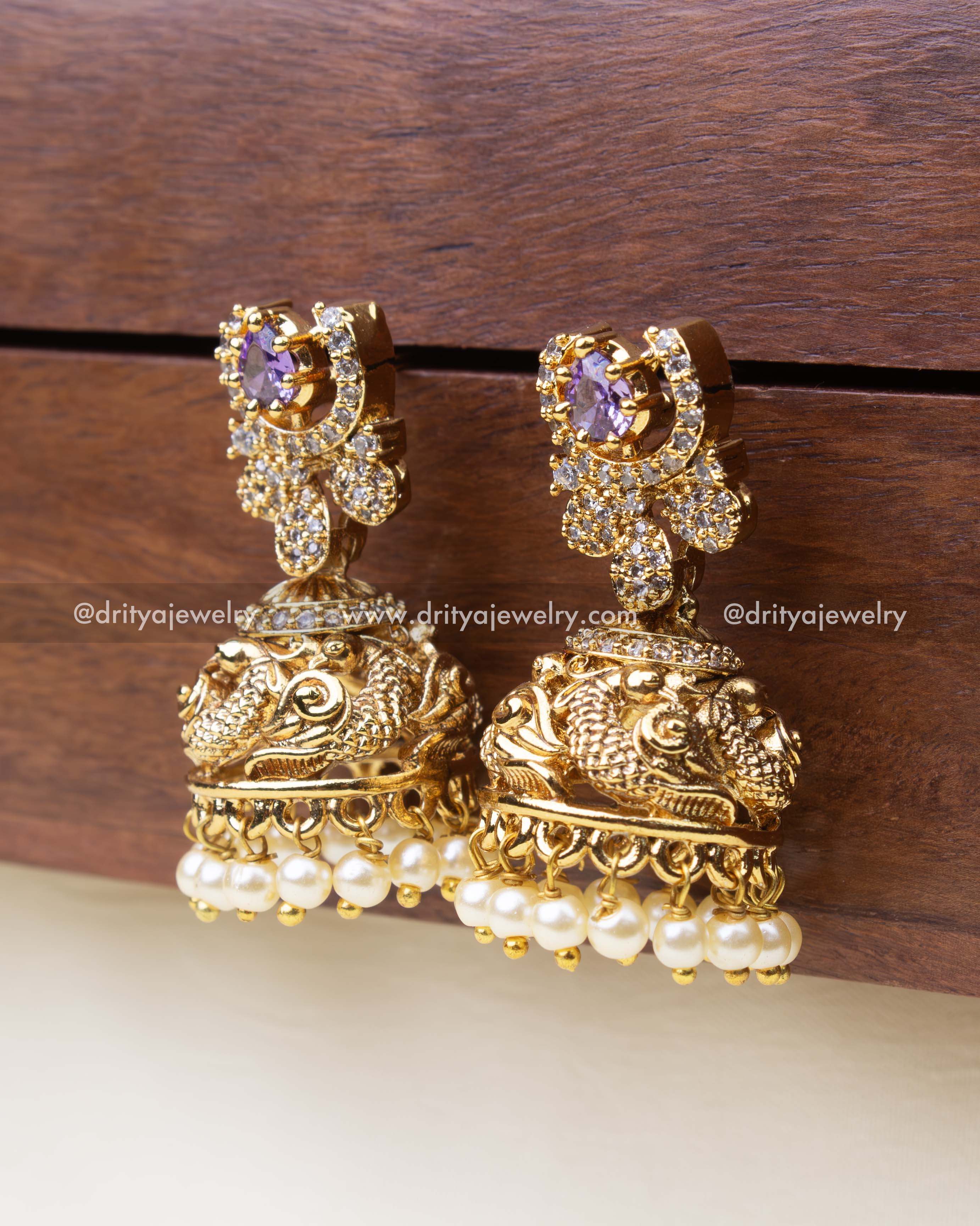 Close-up of temple earrings with purple stone, CZ embellishments, and pearl drops.