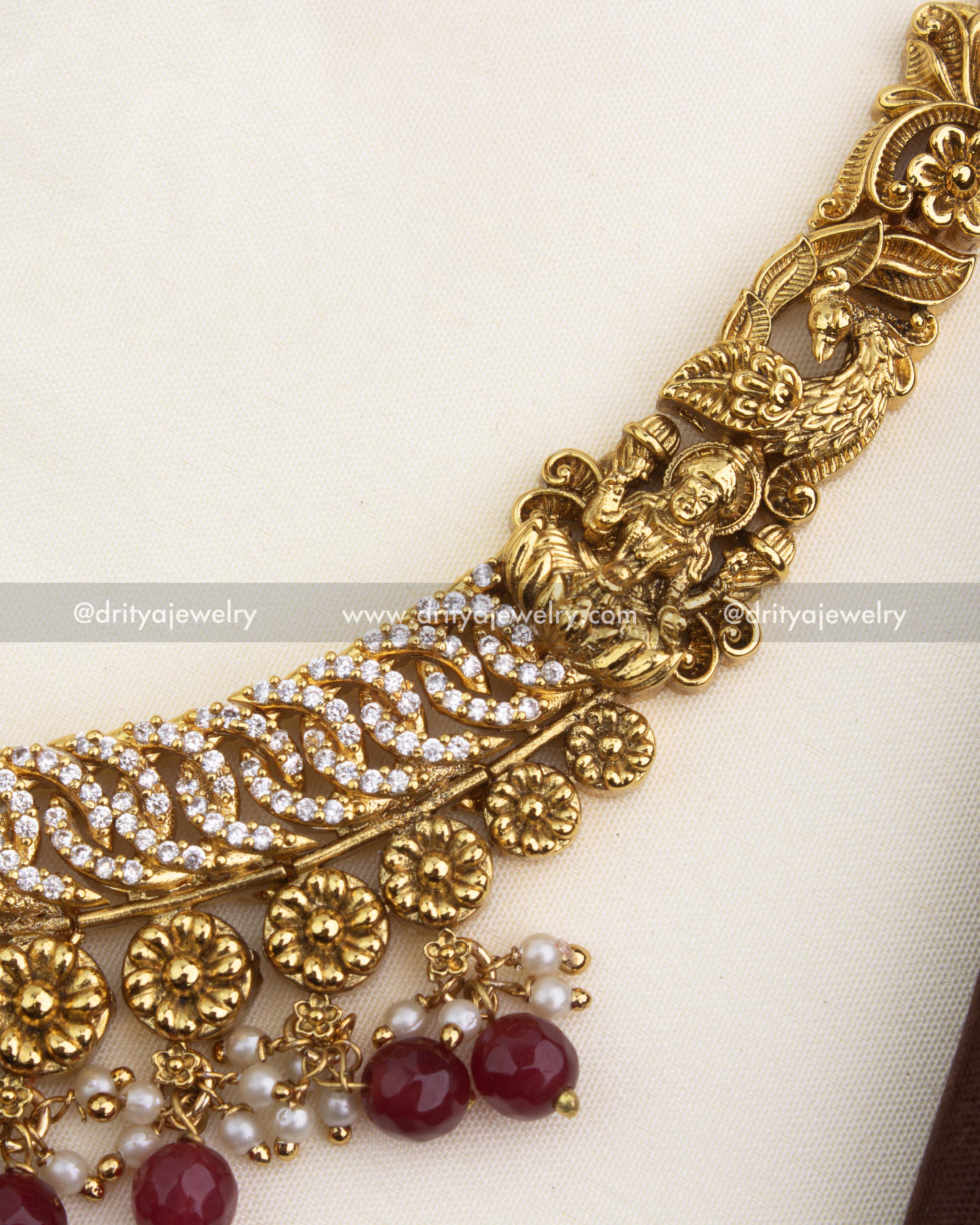 Close-up of peacock and floral nakshi carvings embellished with CZ stones and ruby accents.