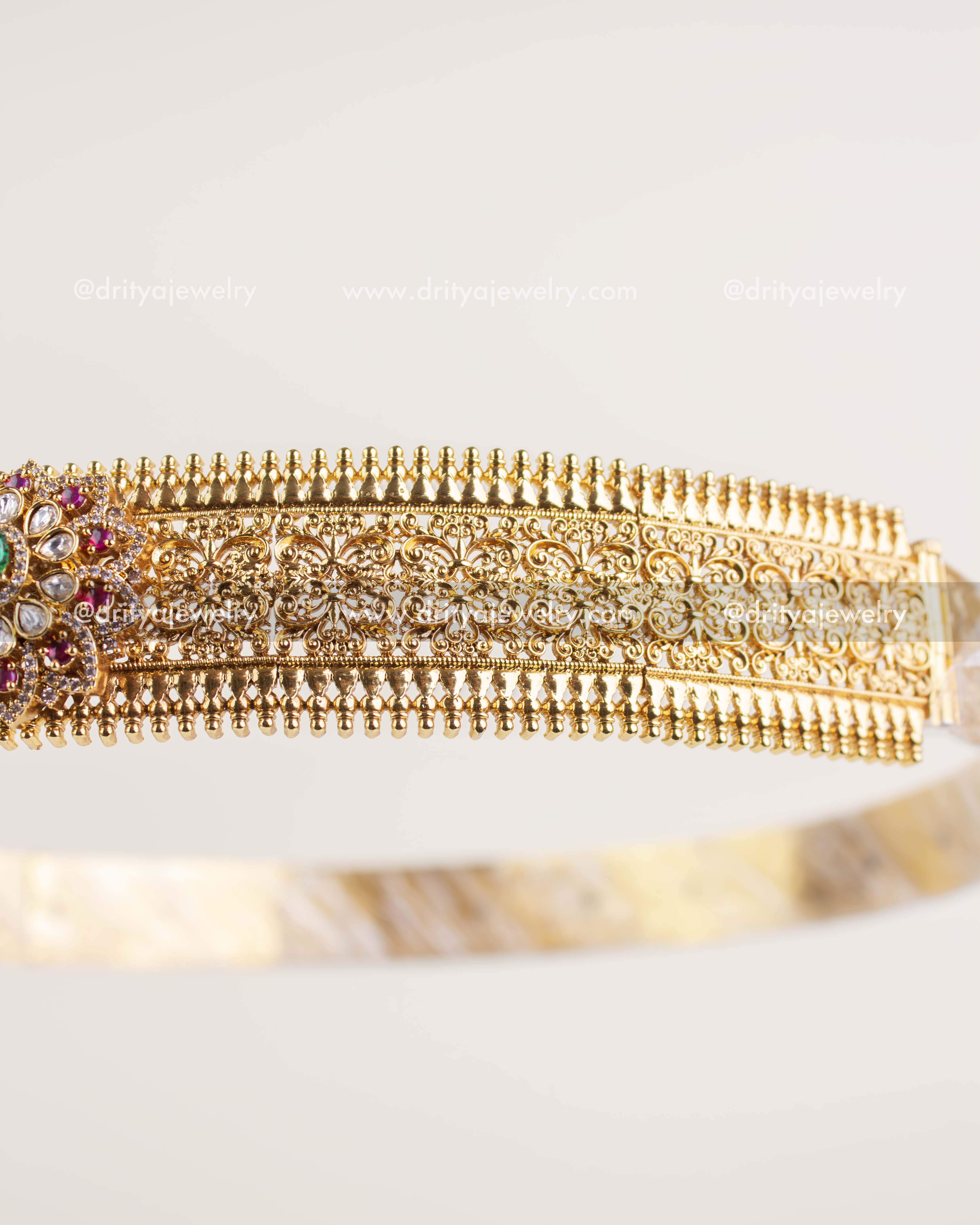 Close-up of engraved antique gold waist belt with textured pattern and kundan work.
