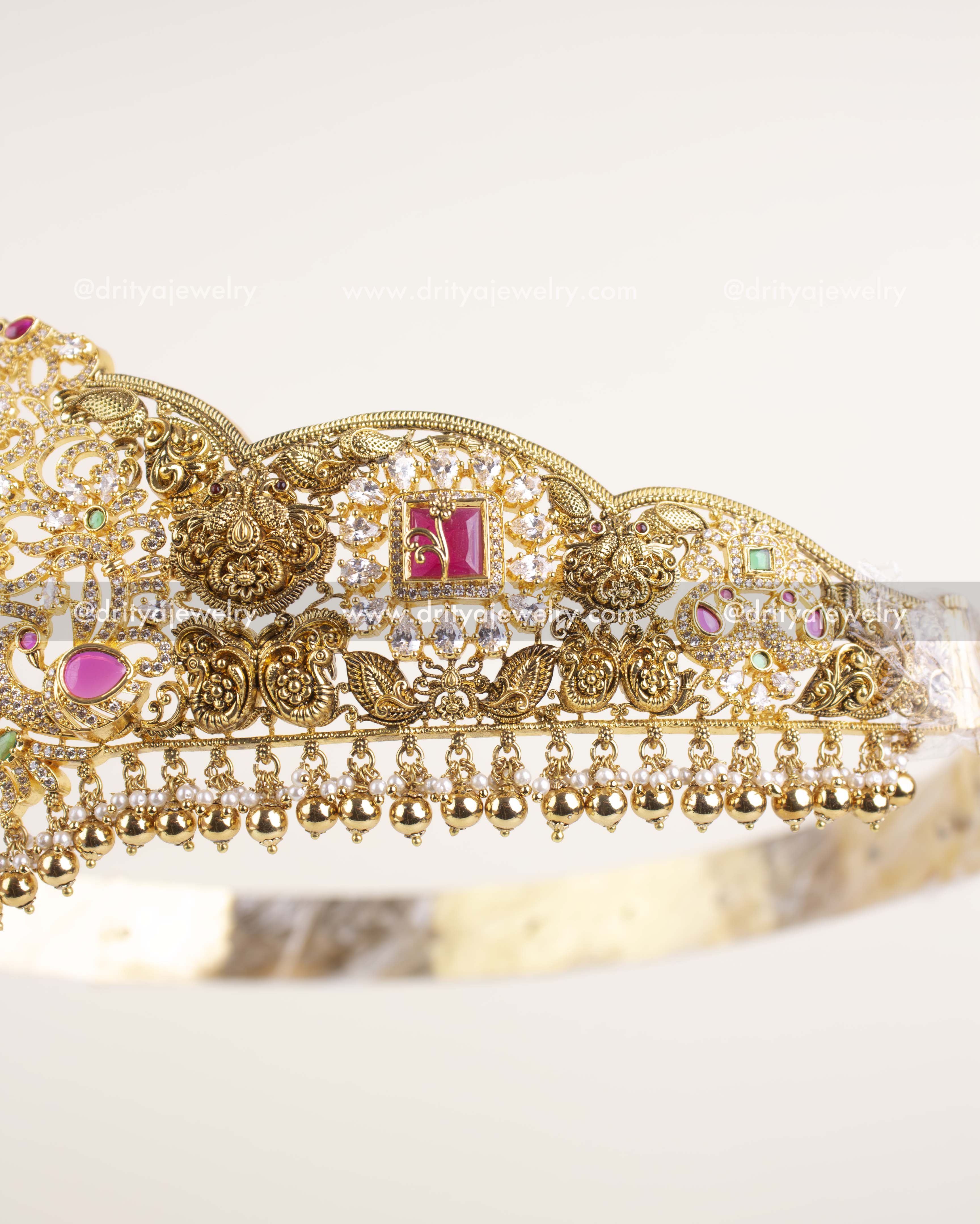 Detailed side view showing nakshi carvings, ruby stones, and golden bead drops on waist belt.
