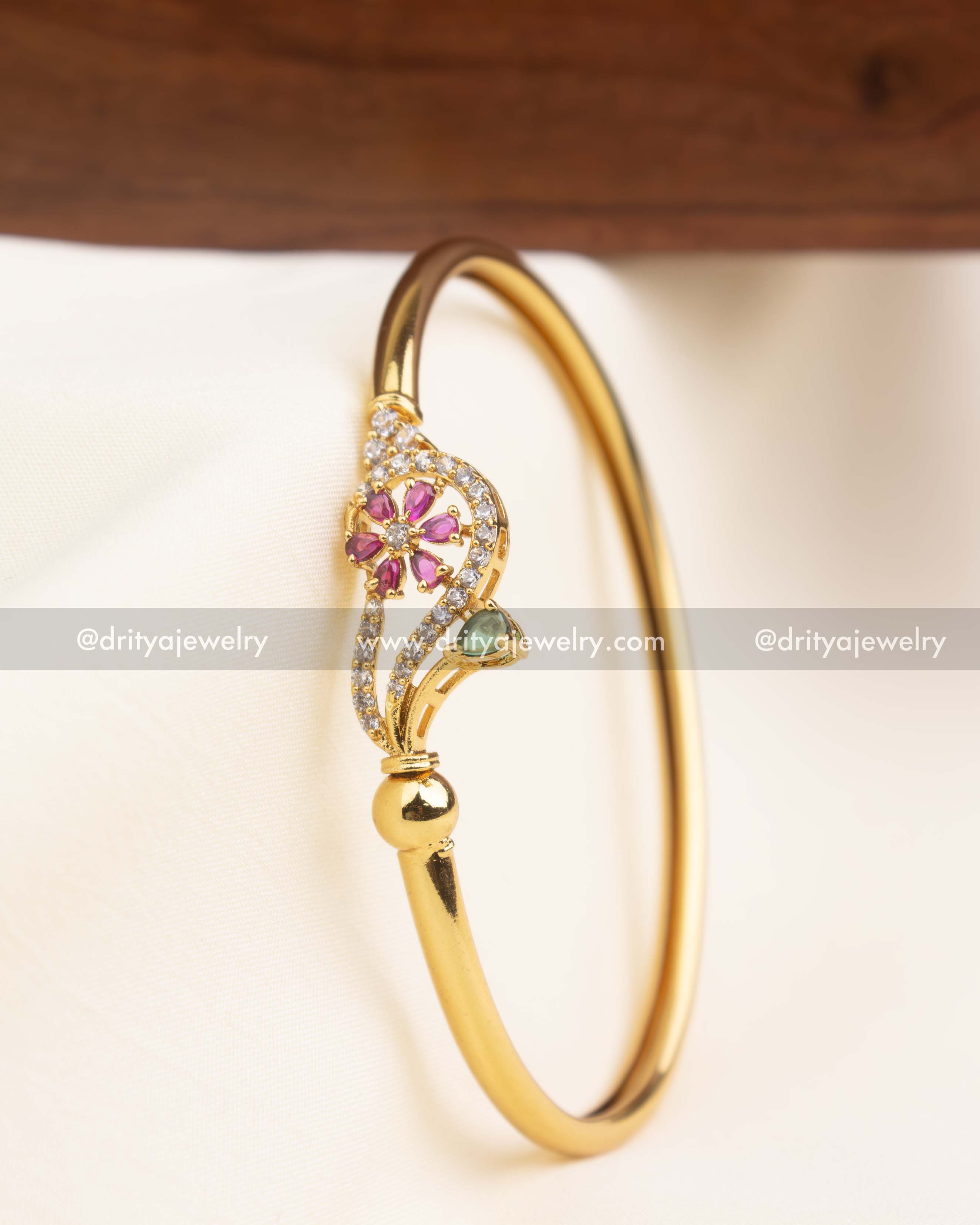 Side profile of adjustable open kada featuring pink flower design and green stone accent
