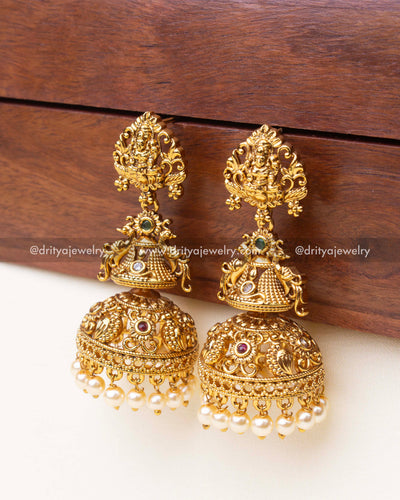 Side profile of large temple Jhumka earrings with antique gold finish and hanging pearls.