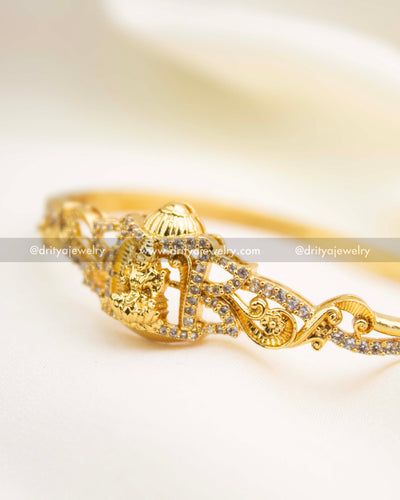 Gold temple kada with intricate scrollwork and sparkling CZ embellishments.